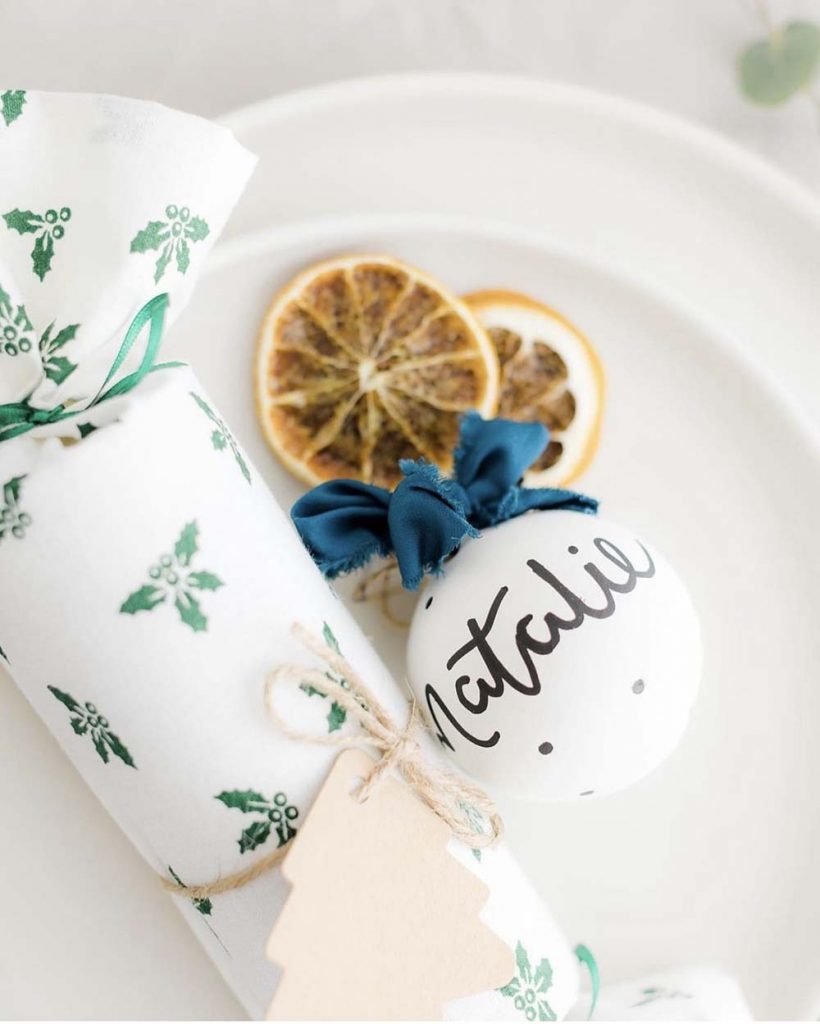 Personalised ceramic bauble styled next to a reusable fabric cracker.