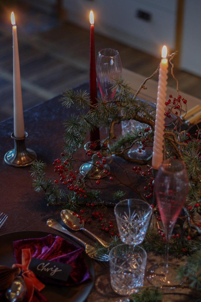 overhead shot of a winter tablescape. Velvet table runner with vintage cutlery, glassware and candle sticks.