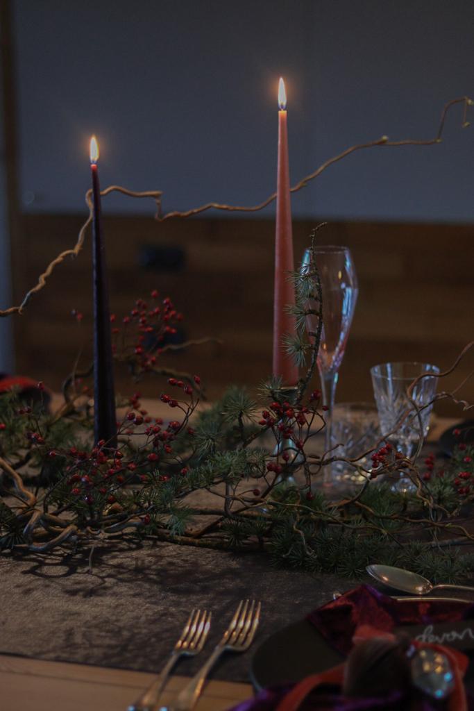 silvery toned evergreen and delicate red berries styled with silver candle sticks and coloured tapered candles.