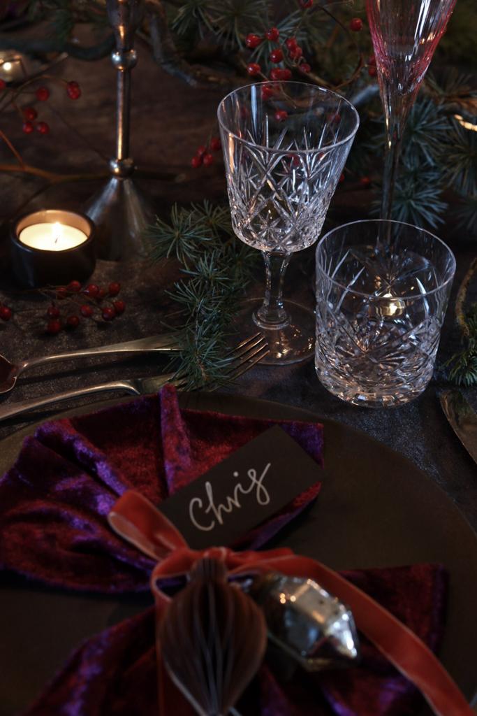 Hand written black place name with white ink. Vintage cut glass glassware, dark velvet table runner, moody and atmospheric table styling
